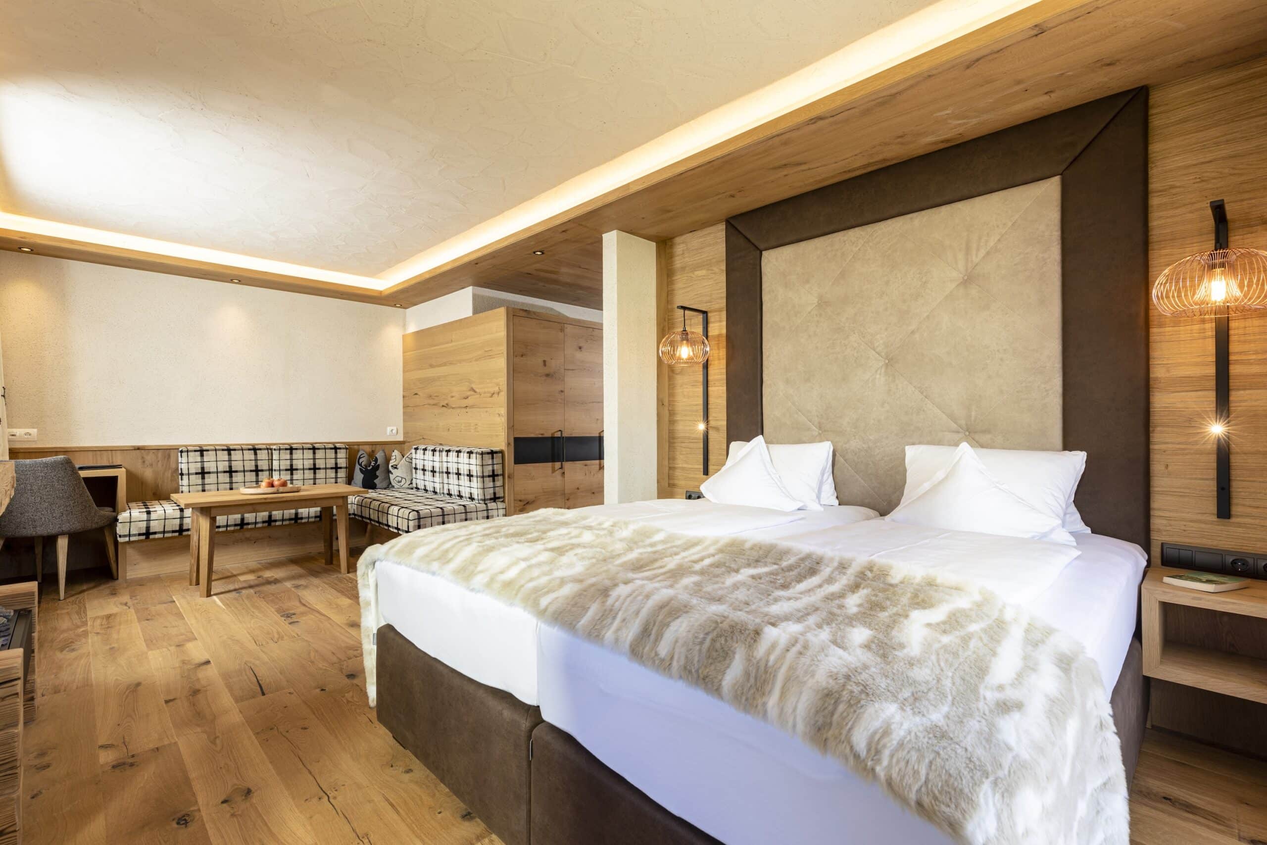 Modernes, stilvolles Schlafzimmer mit einem großen Doppelbett mit weißen Kissen und einer Kunstfelldecke, Holzwänden und eleganten Hängeleuchten.