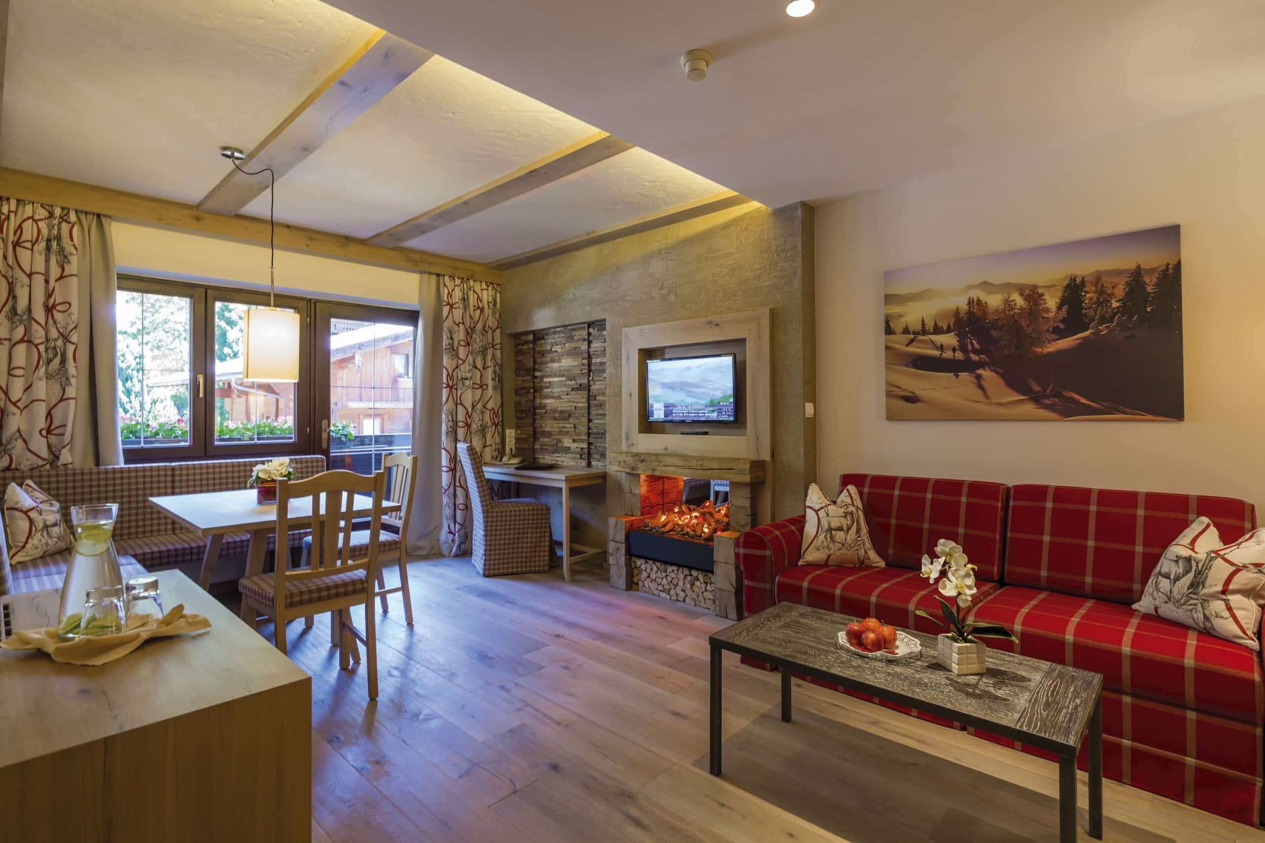 Gemütliches Wohnzimmer im Chalet-Stil mit rotem Sofa, Holzmöbeln und Kamin.