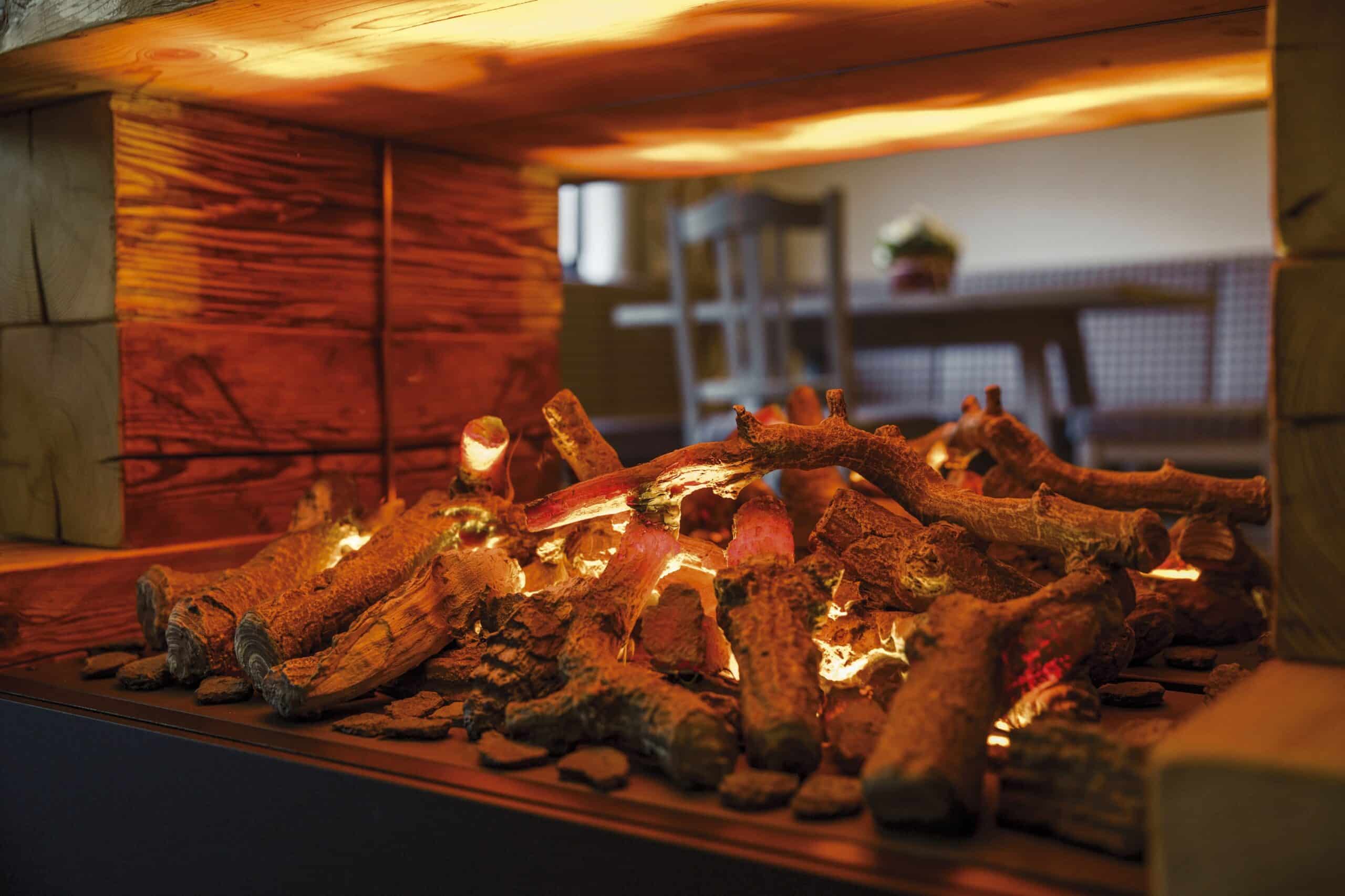 Künstliches Kaminfeuer mit leuchtenden Holzscheiten in einer gemütlichen Holzumrandung.