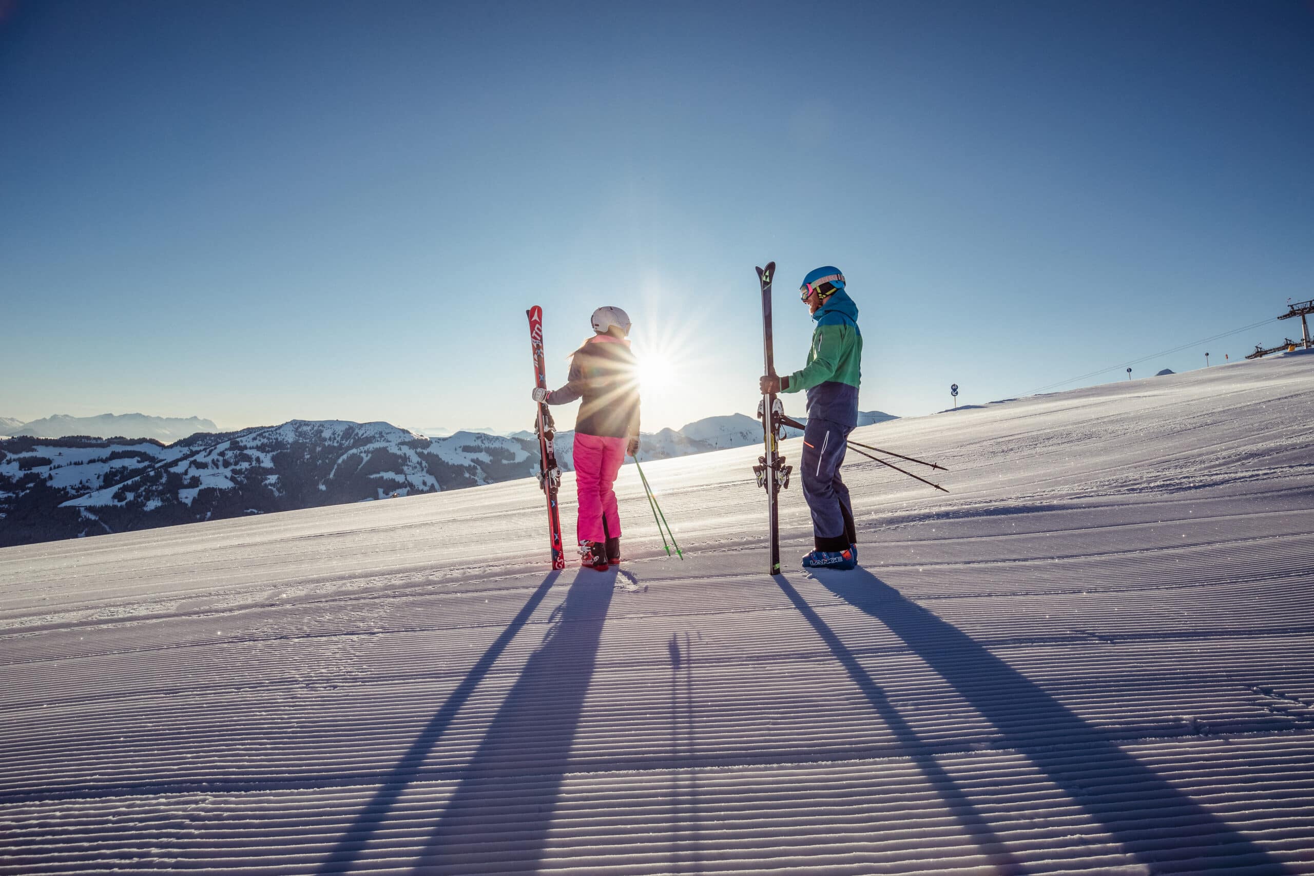 Schifahrer - frisch präparierte Piste - tragen Ski in der Hand - Sonnenaufgang