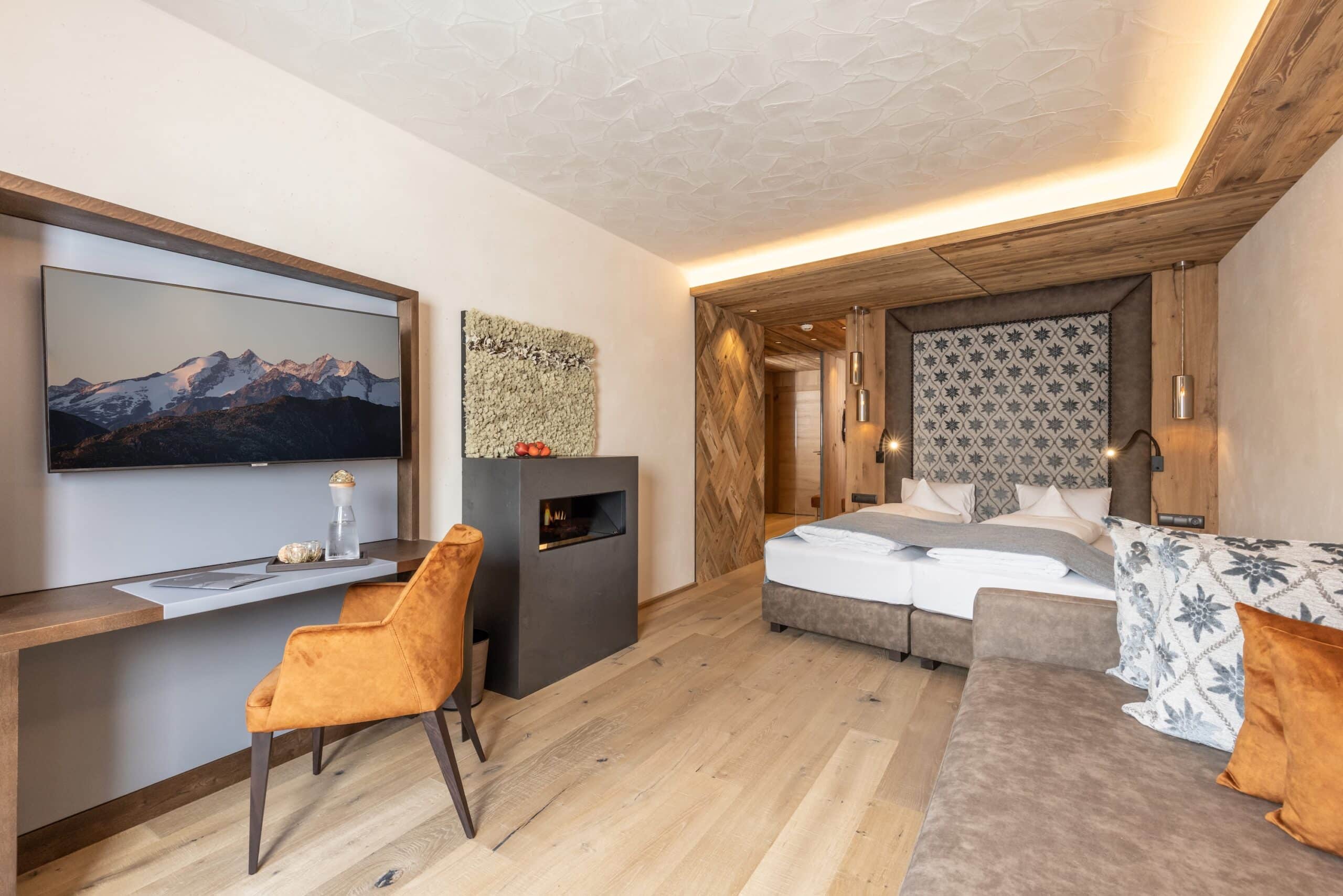 Doppelzimmer Naturblick, Blick ins Zimmer mit Doppelbett, Schreibtisch, elektr. Ofen, Holzboden, warme Farben