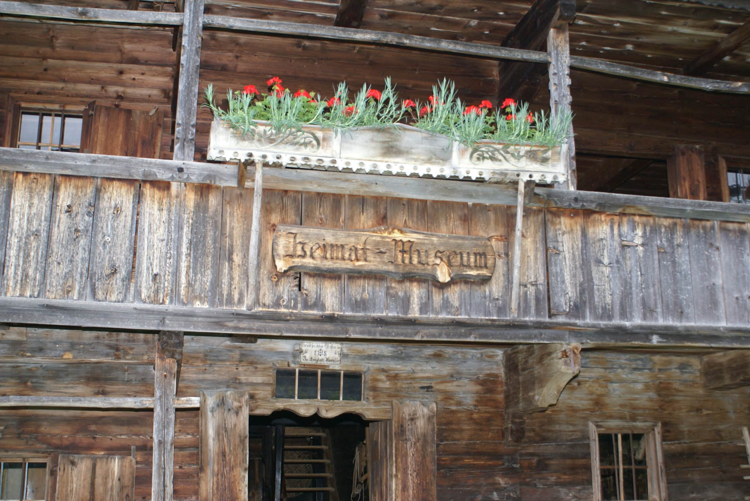 Holzfassade eines Bauernhauses mit einem Schild, auf dem