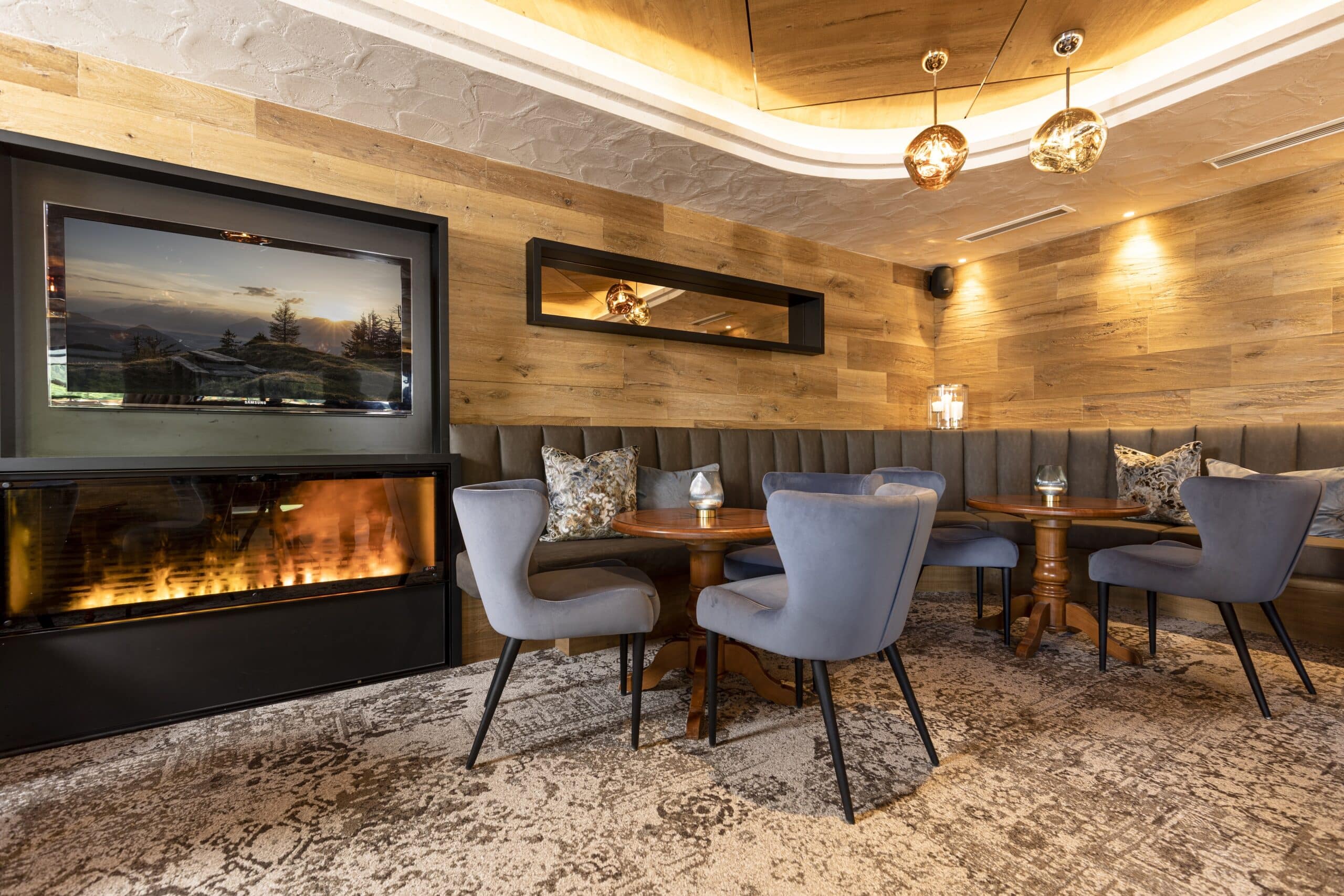 Modernes Restaurant-Interieur mit gemütlichen blauen Stühlen, Holzwänden und einem Kamin.
