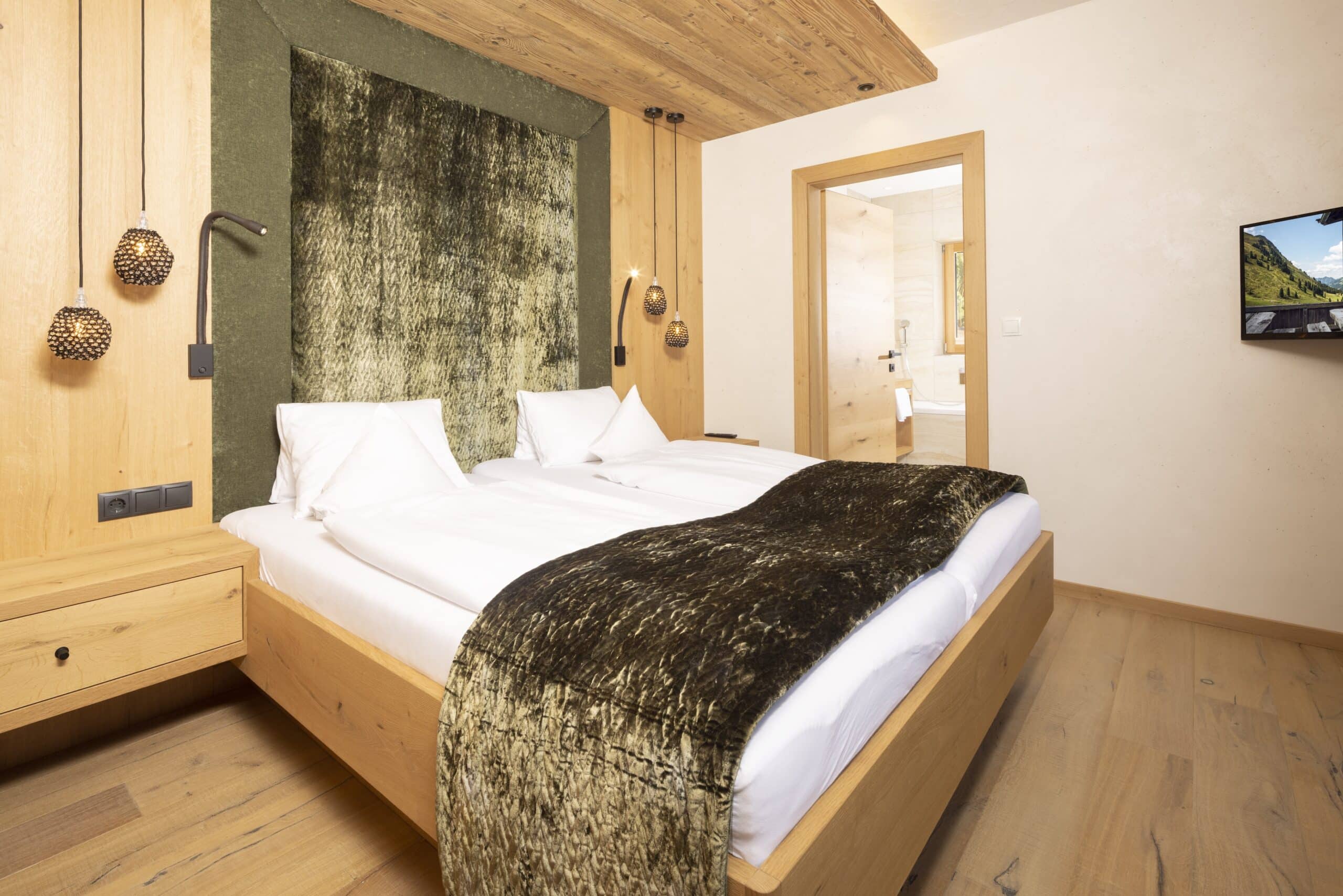 Gemütliches, modern eingerichtetes Schlafzimmer mit Doppelbett, hölzernen Möbeln und dekorativen Hängeleuchten.