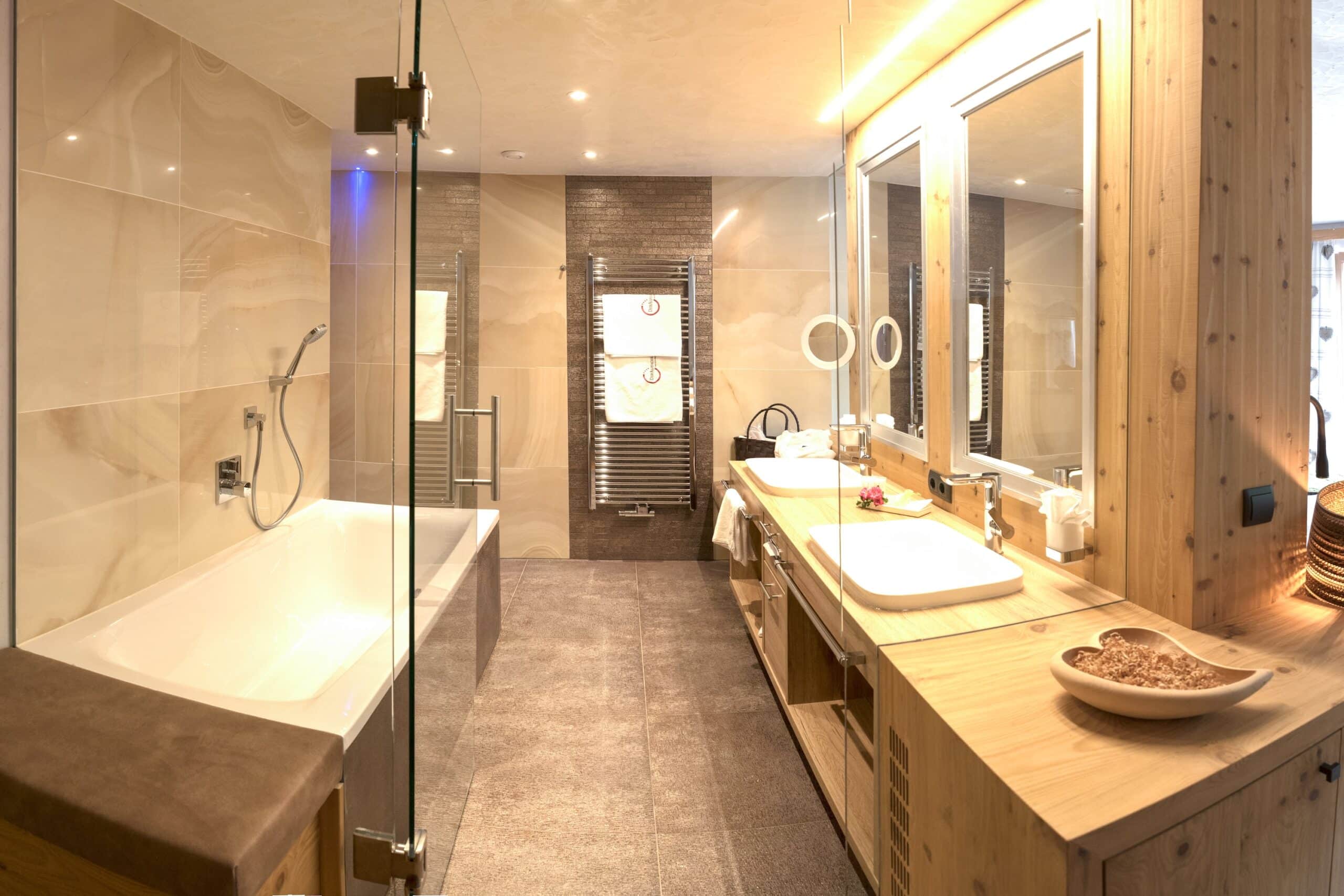 Modernes Badezimmer mit einer freistehenden Badewanne, einer Duschkabine, einem Doppelwaschtisch aus Holz und großen Spiegeln.