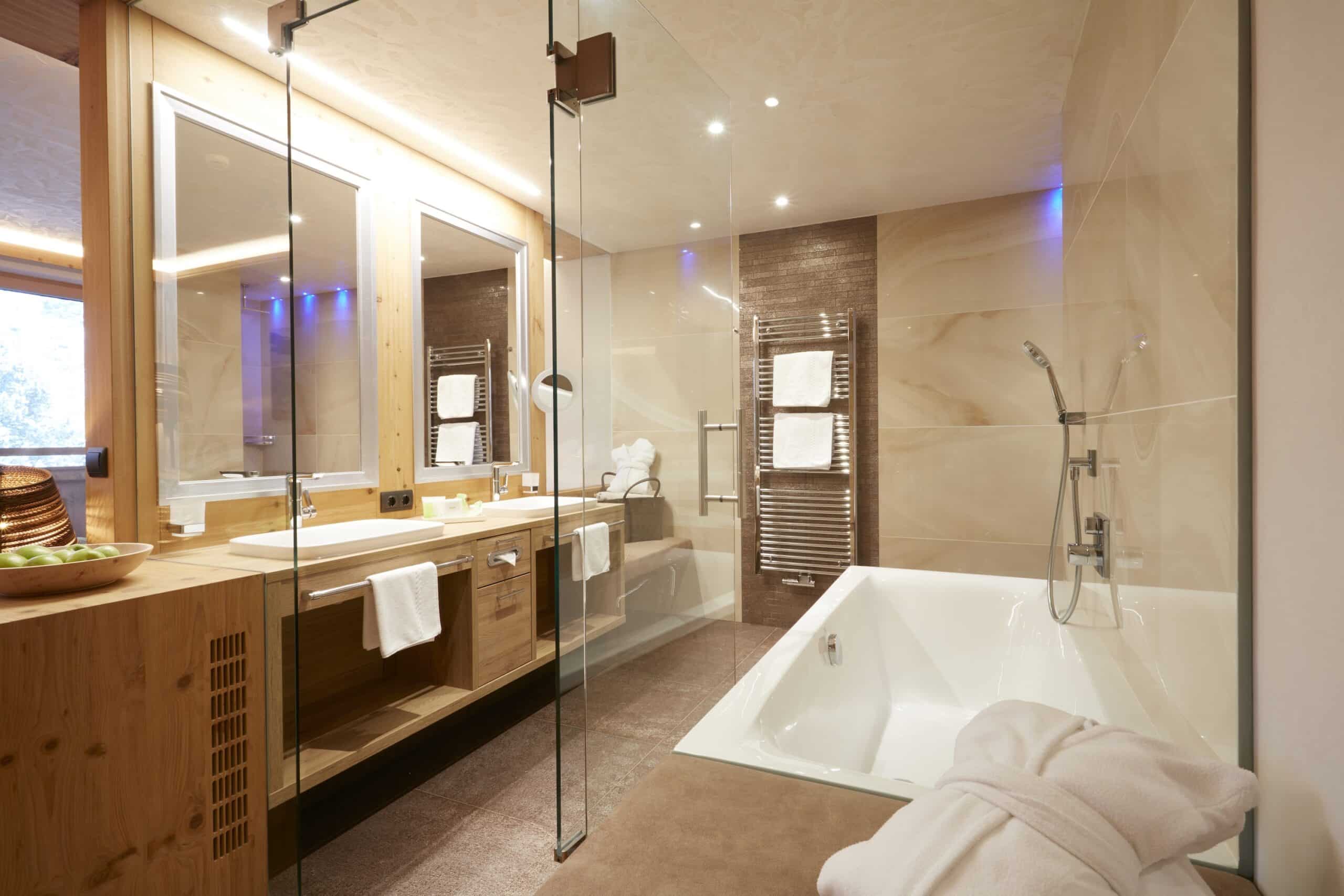 Modernes Badezimmer mit großer Badewanne, Glasdusche und hölzernem Waschtisch.