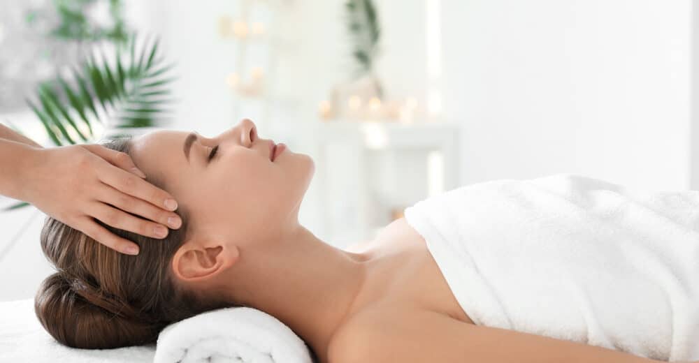Frau erhält eine entspannende Kopfmassage in einem hellen Wellness-Spa.