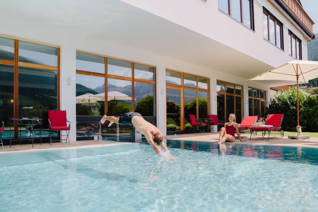 Sommerurlaub im Hotel mit Pool in den Bergen – Gäste entspannen am Wasser