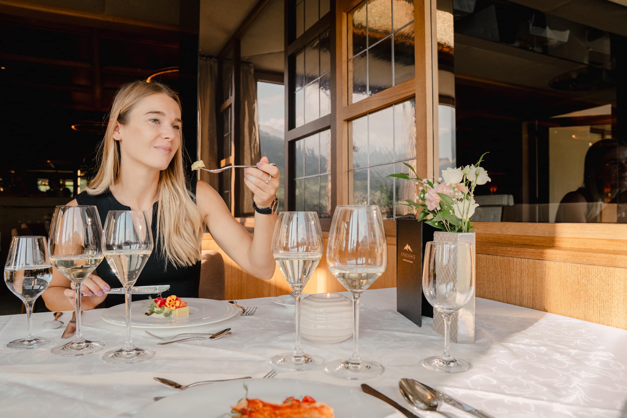 Junges Paar genießt das 6-Gang-Abendmenü mit Weinbegleitung im Panoramarestaurant des Hotel Alpbacherhof in Tirol