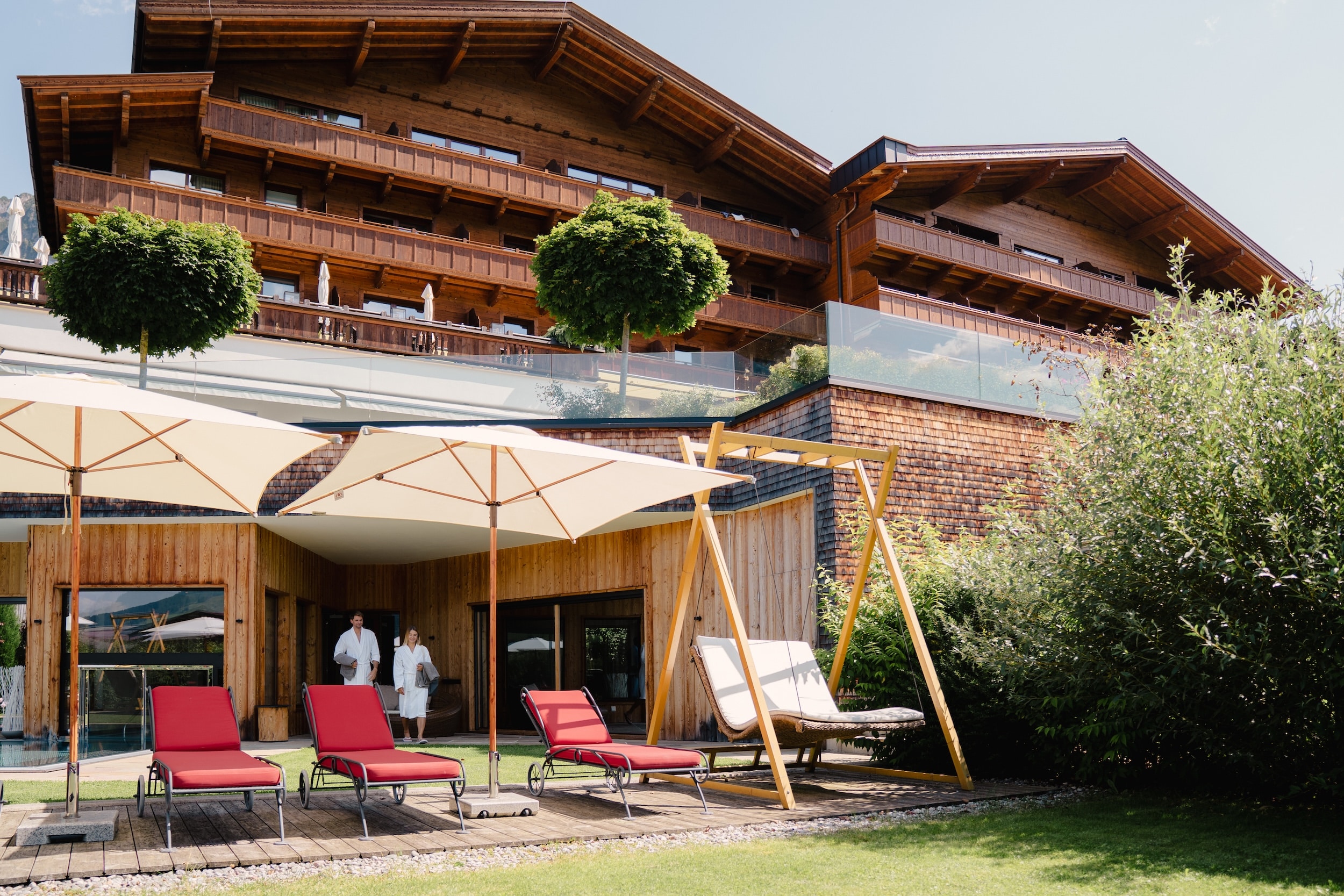 Paar in Bademänteln entspannt gemeinsam auf einer Liege im Hotelgarten des Alpbacherhof