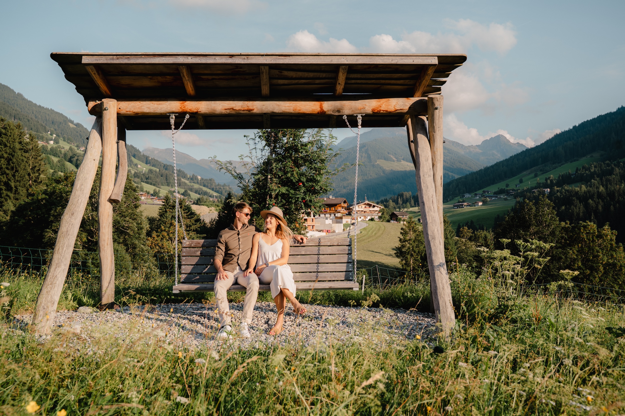 Pärchen sitzt auf Schaukel mitten in der Panoramawiese des Hotel Alpbacherhof in Tirol